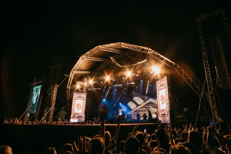 Vibrant live performance with crowd at an outdoor concert stage.