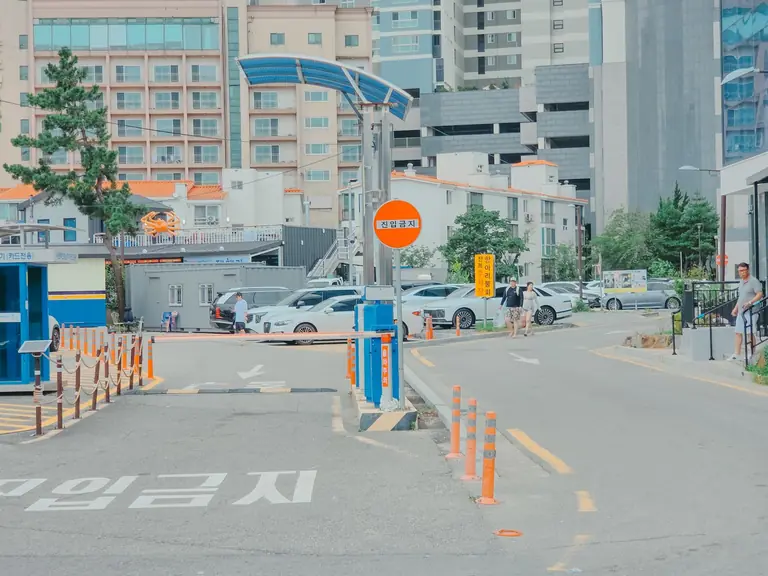 A bustling urban street in Gangwon-do, South Korea, featuring parked cars and modern buildings.